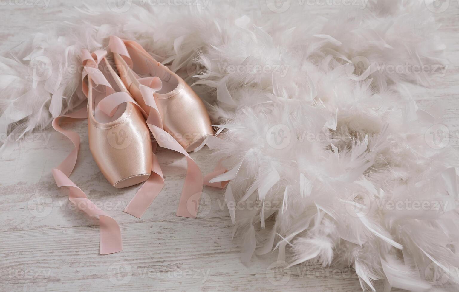 Pastel pink ballet shoes background. New pointe shoes with satin ribbon lay on white rustic shubby chic wood near feather boa, view with copy space photo