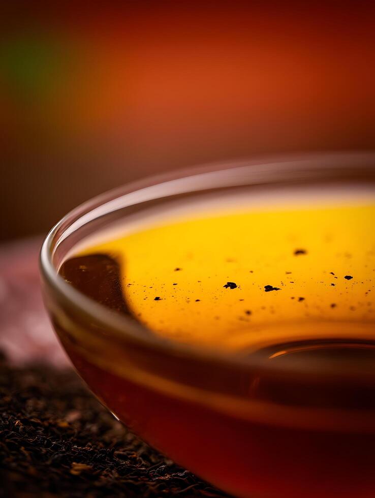 Close Up of Amber Liquid in a Glass Bowl, Tea Leaves in Focus. photo