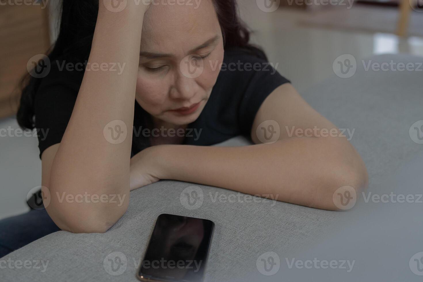 Cropped shot of dissatisfied mature Asian woman using smartphone indoors Bad News Concept. photo