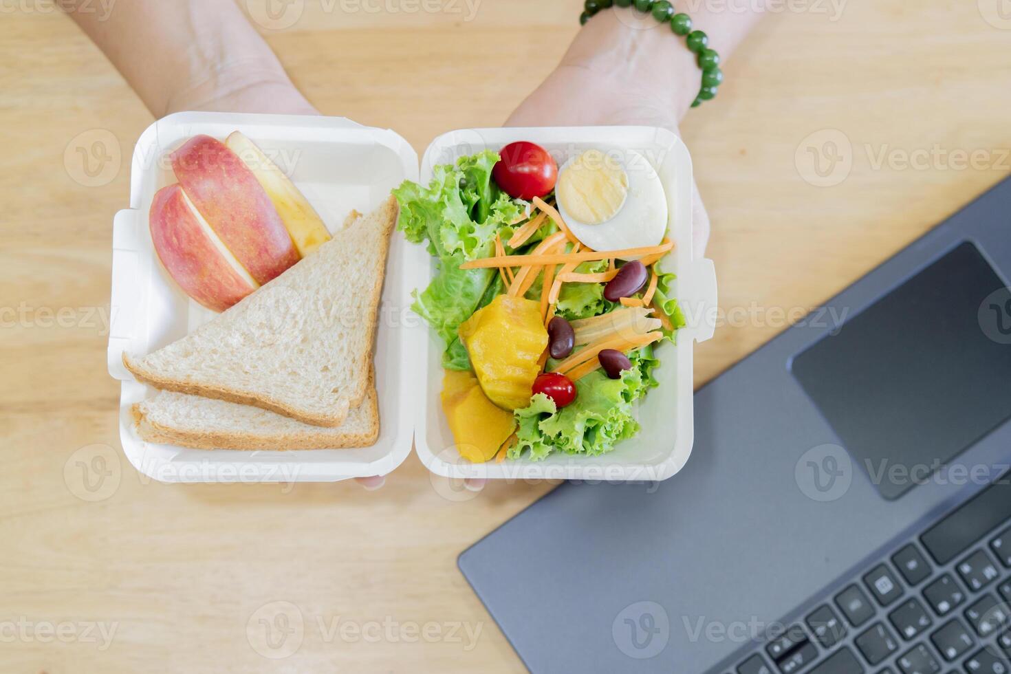 Female hands hold healthy food delivery box having lunch at work from home office. photo