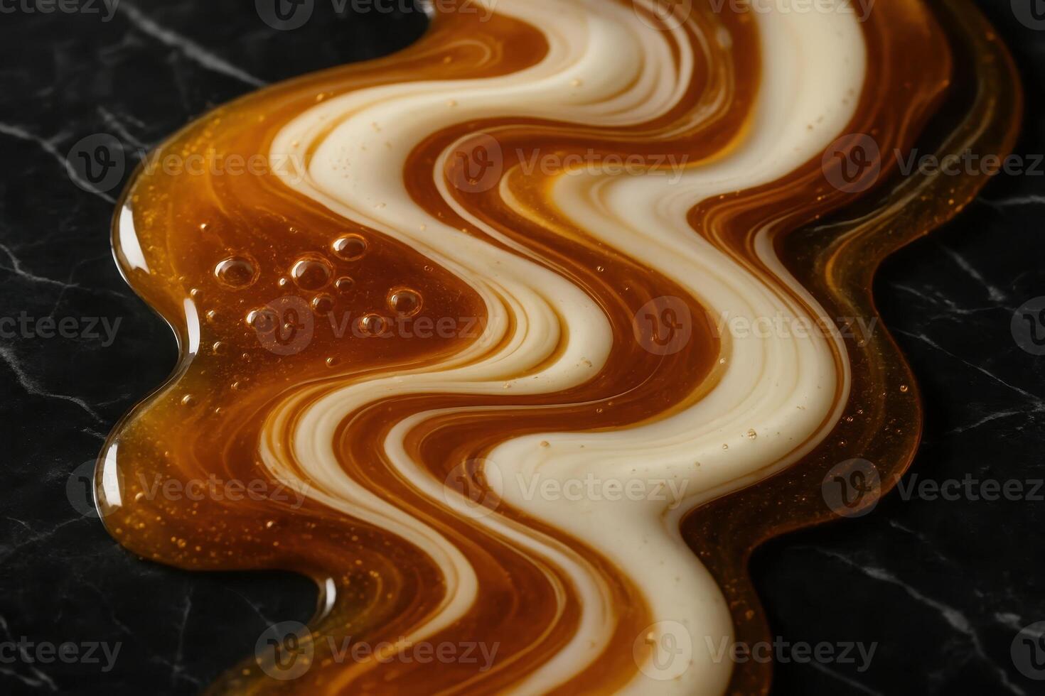 Viscous golden honey and creamy white milk swirling together on a black marble surface photo