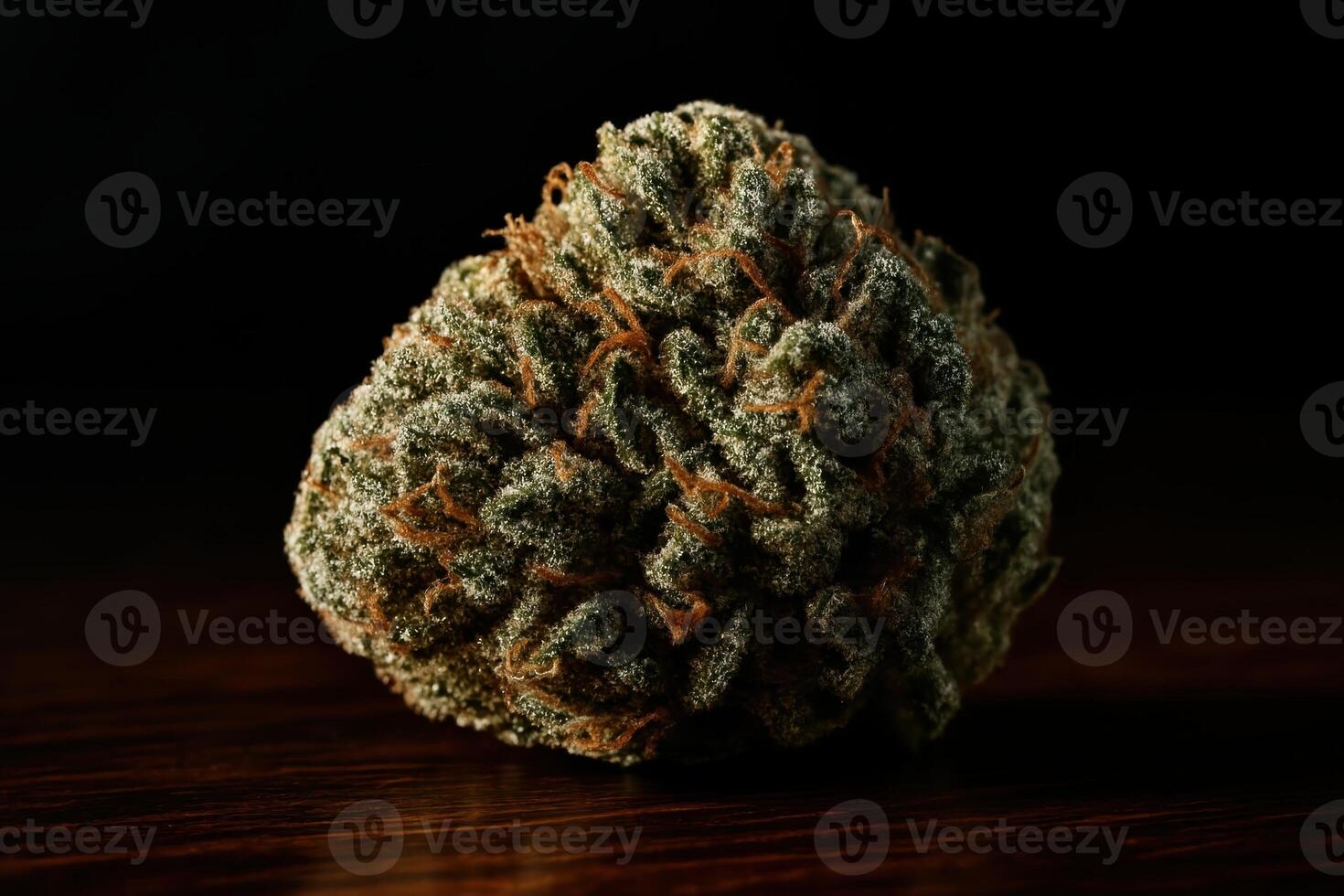 High detail macro shot of a single cannabis bud on dark wood, showing trichomes and orange hairs photo