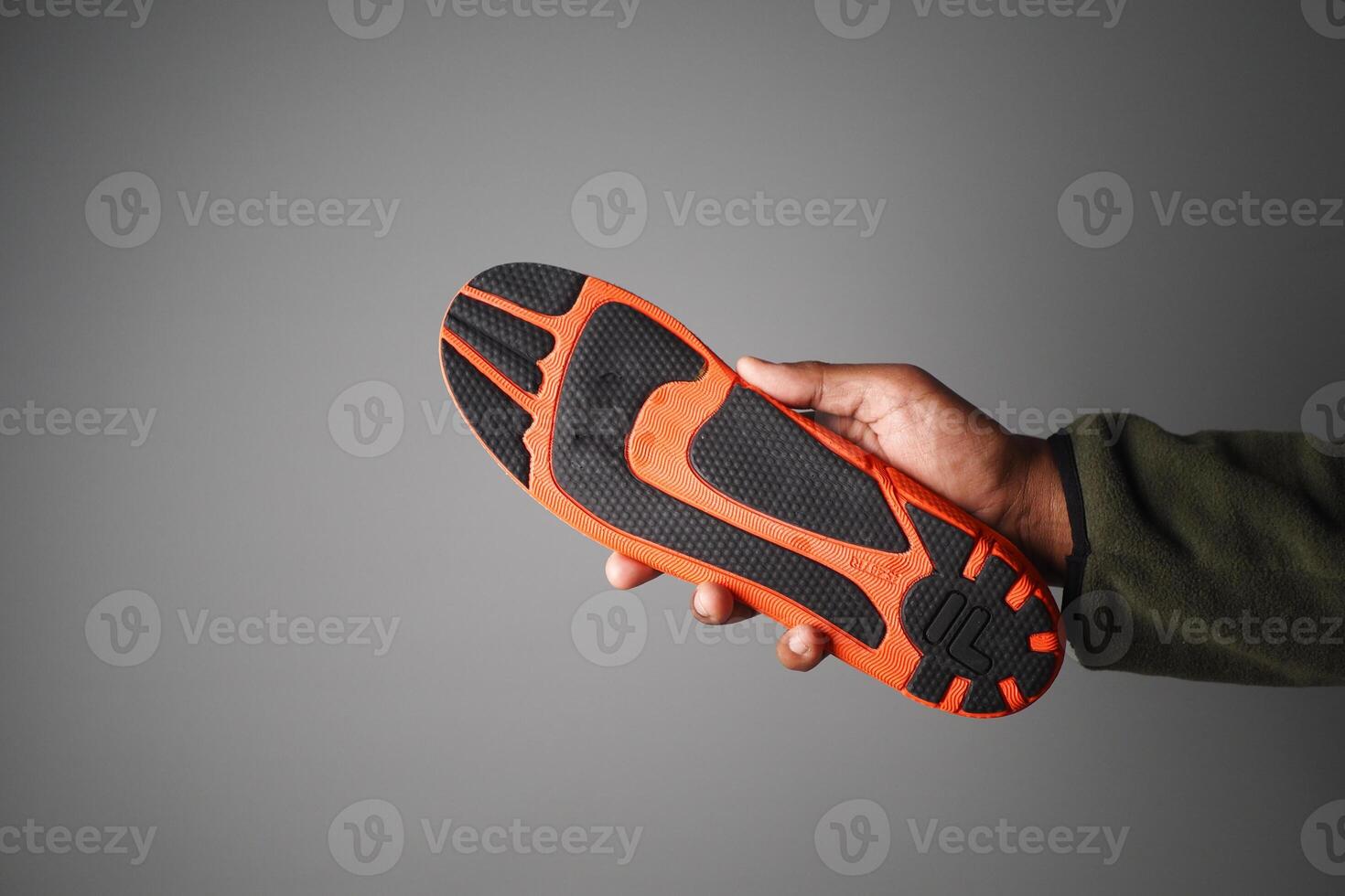 Hand holding an orange and black athletic shoe sole photo