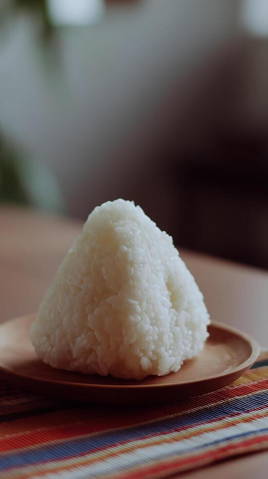 Close Up of a Triangular Onigiri Rice Ball on a Wooden Plate. photo