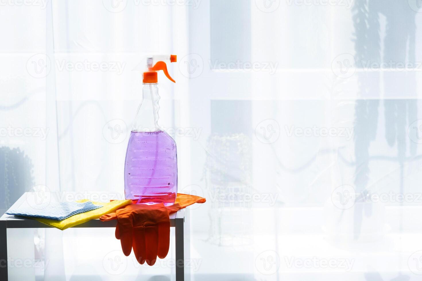 A bottle of cleaning solution and gloves on a table photo