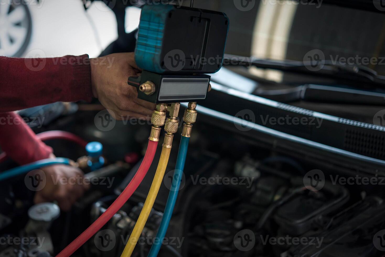 A man is holding a hose and using a meter to check the temperature of the engine photo