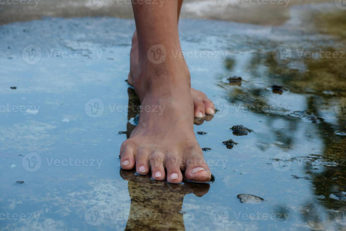 Barefoot Person Walking in Shallow Water Reflects Ground Texture photo