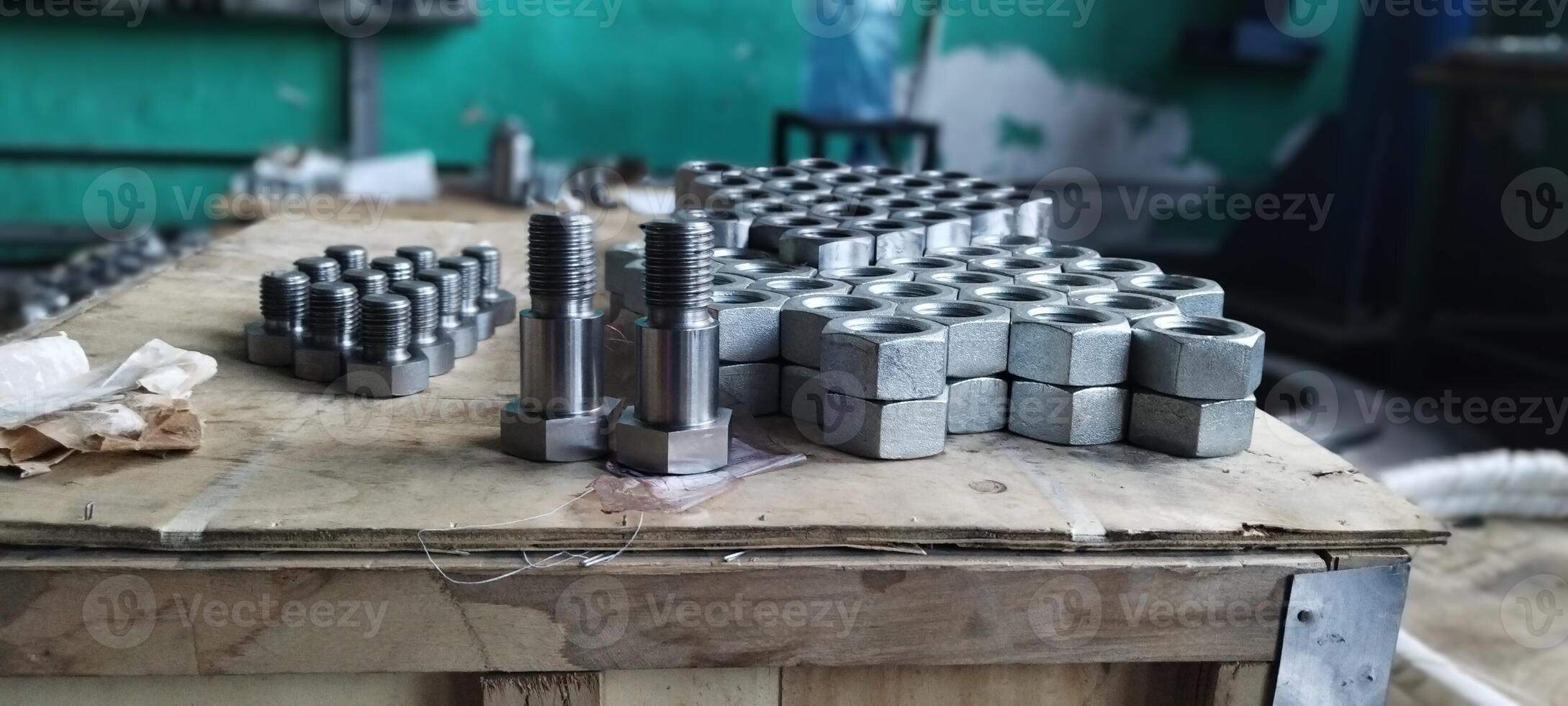 Steel bolts and nuts. Industrial fasteners displayed on a wooden surface, with a blurred workshop background. Flanged steel hex nuts. Close-up of new metal bolts and nuts. Mechanical engineering. photo