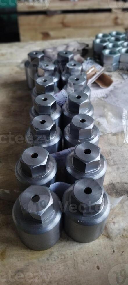 Metal components with a hexagonal head. Industrial fasteners on a wooden surface. Mechanical engineering. Is used in such fields as mechanical engineering, oil and gas, metallurgy, chemical. photo