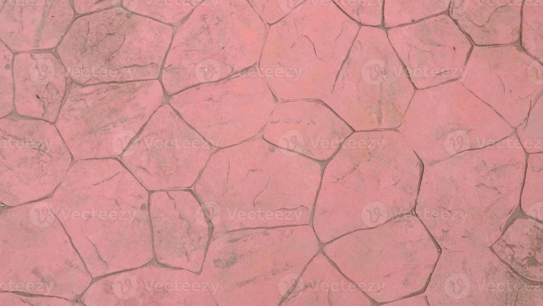 A pink cobblestone pavement with irregular shapes and dark gray grout lines, creating a textured and patterned surface, ideal for backgrounds photo