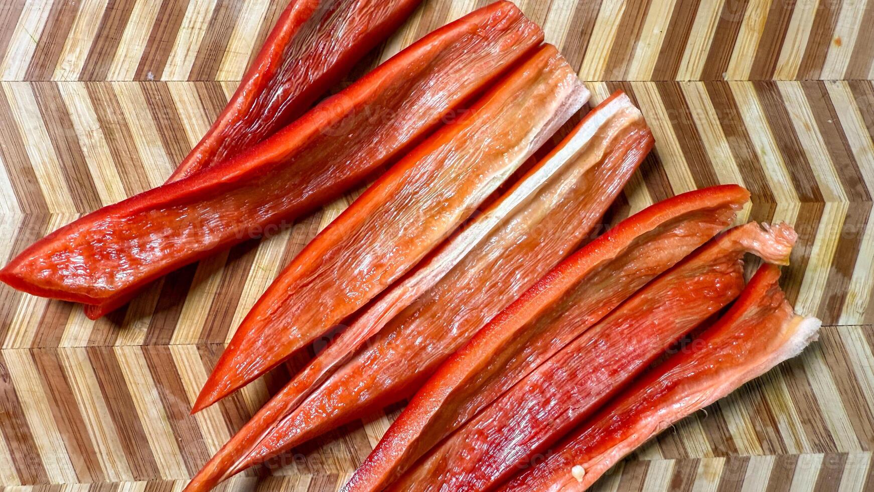 Carved crimson paprika slivers strewn like confetti on herringbone wood, celebrating Lunasa harvest and vibrant autumnal equinox feasts photo