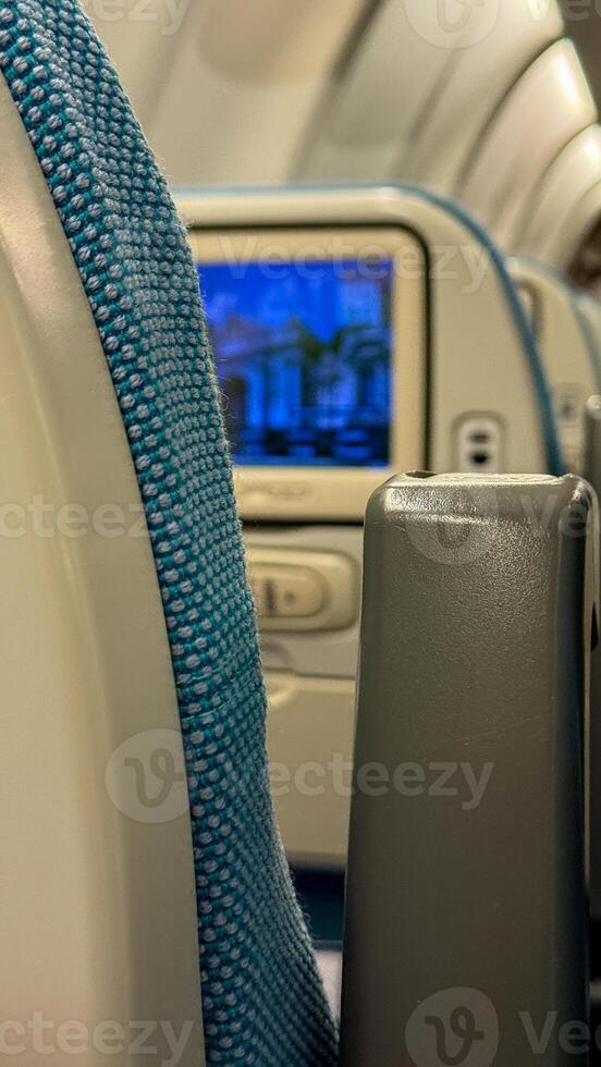 Snug teal airplane seats whisper wanderlust dreams, in flight screen flickering exotic landscapes, Digital Nomad Day anticipation photo