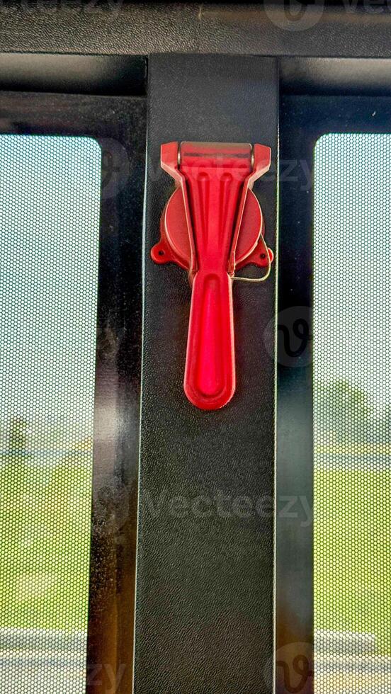 Vivid red emergency hammer poised against bus window, symbolizing unexpected escape routes, aligns with quirky Bus Safety Week narratives photo