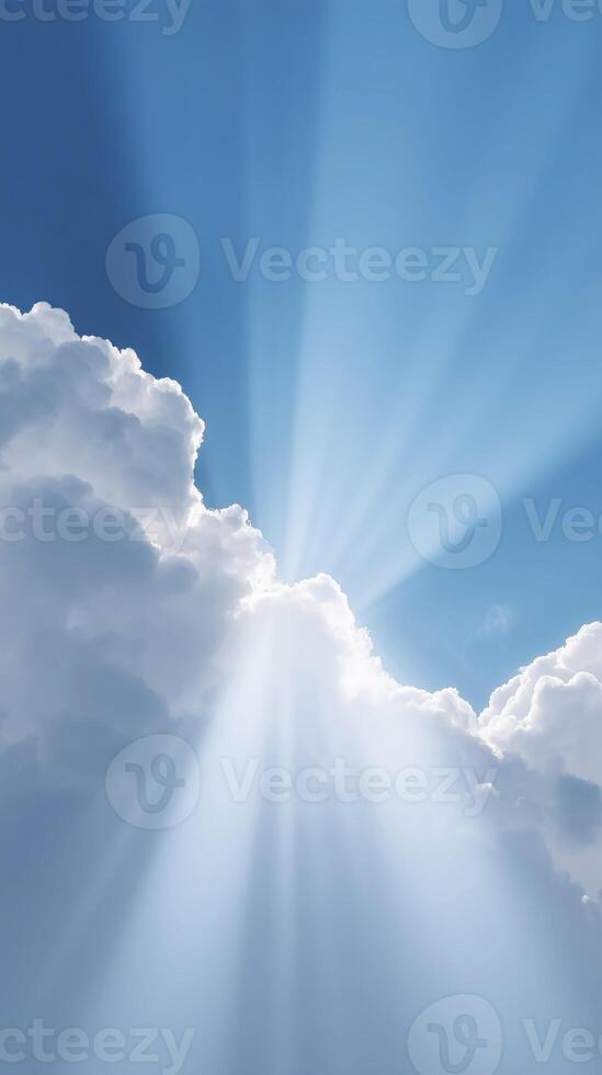 Bright sunlight beams shining through fluffy white clouds in a clear blue sky, creating a serene and uplifting atmosphere, perfect for nature-themed projects and backgrounds photo