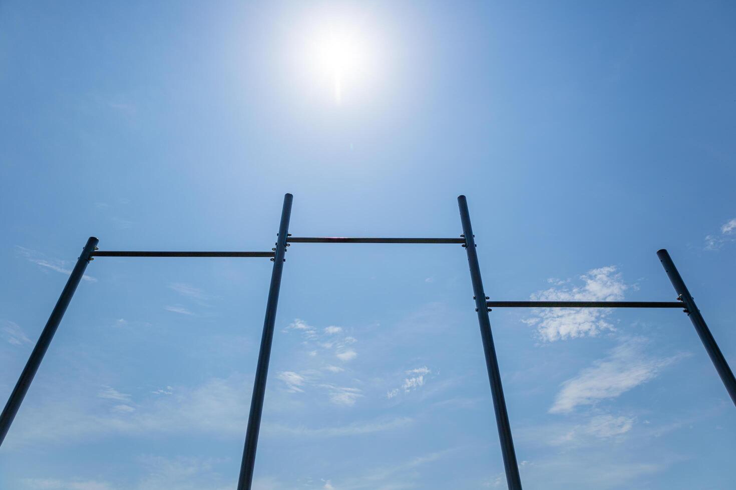 Parallel horizontal bars stand tall against a blue sky, perfect for various workout routines and promoting an active lifestyle outdoors photo