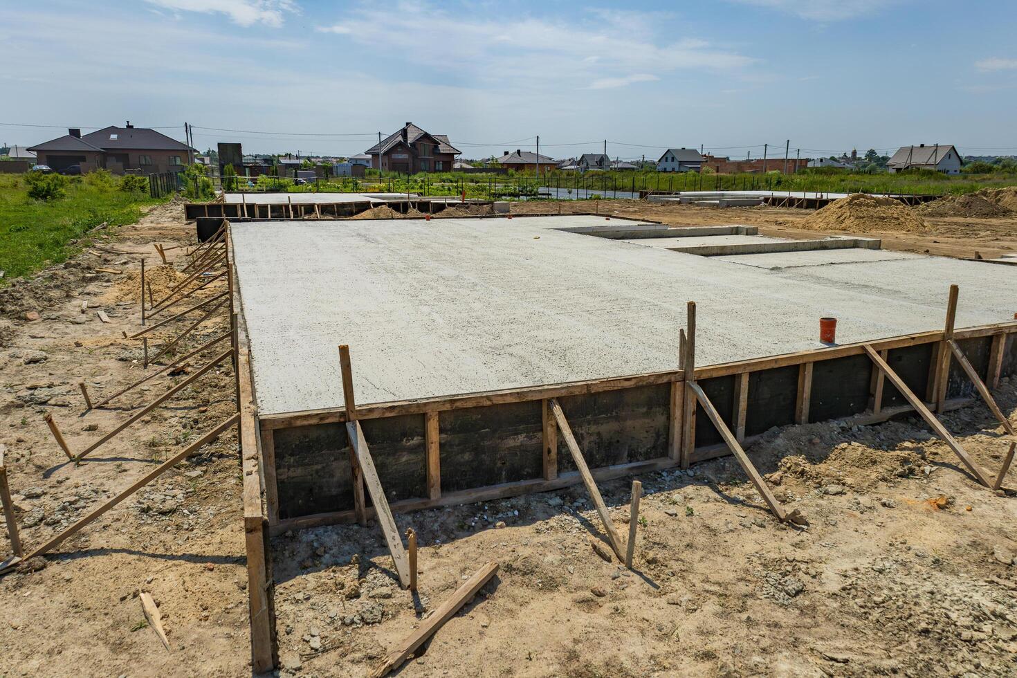 Workers set up a solid foundation for a building in a quiet countryside location as construction progresses under a sunny sky photo