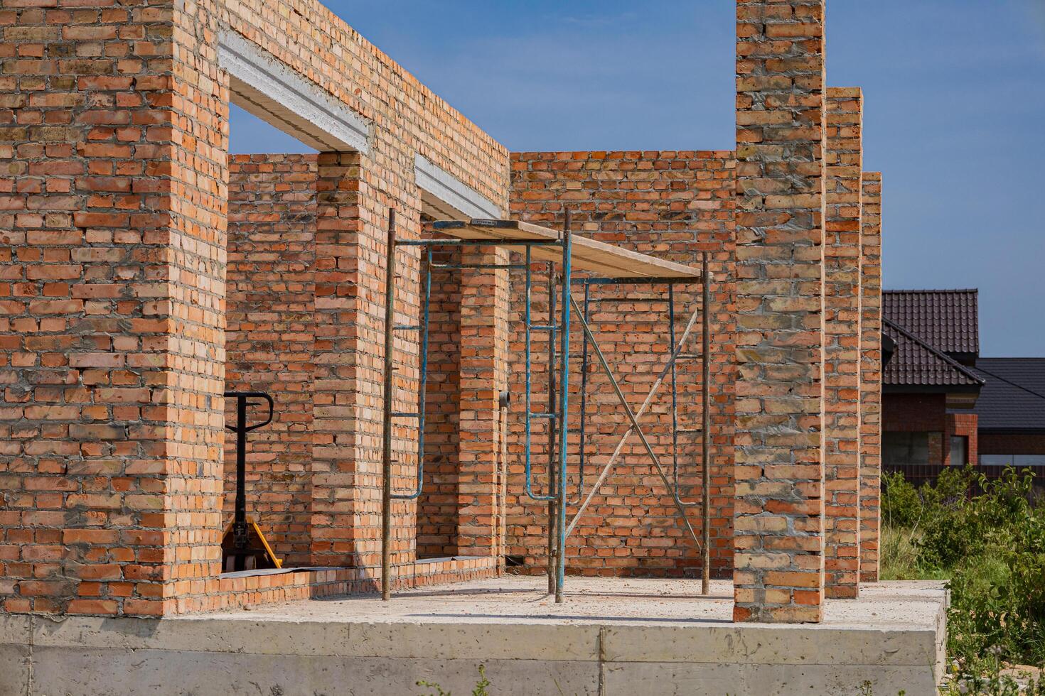 New brick house construction reveals unfinished walls and scaffolding, highlighting ongoing building activities in a residential neighborhood photo