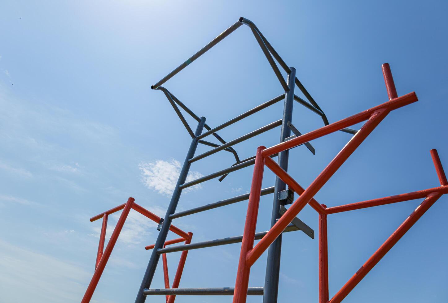 Athletes engage in workouts using parallel bars at a gym in a spacious outdoor area during bright daylight hours photo