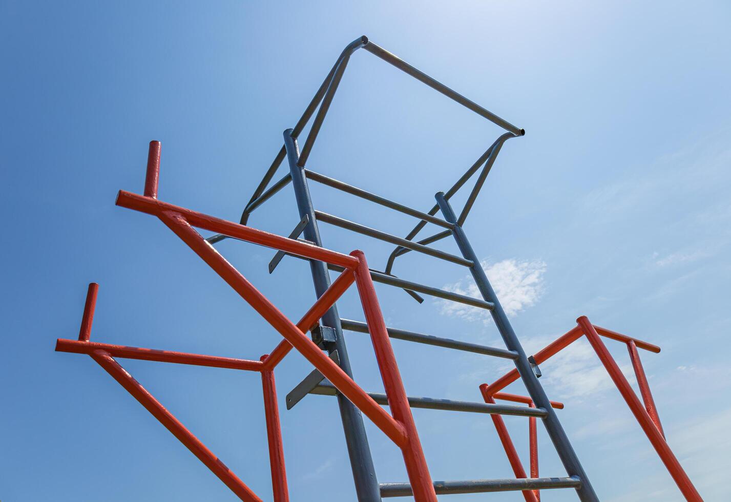 Brightly colored gym structure stands tall against a blue sky, supporting diverse workout activities for fitness enthusiasts photo