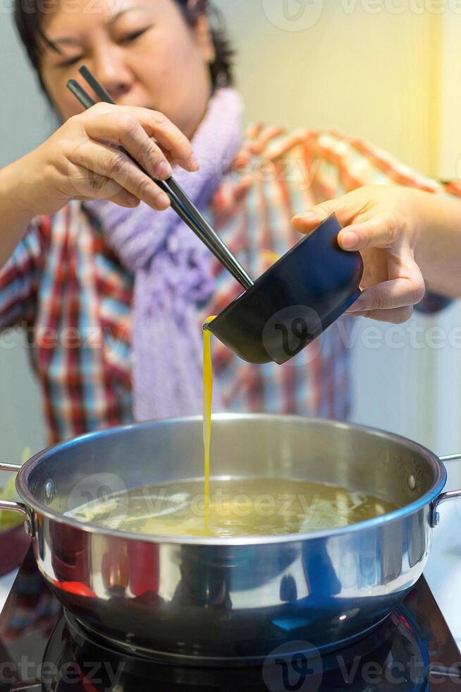 A woman is stirring a pot of soup photo