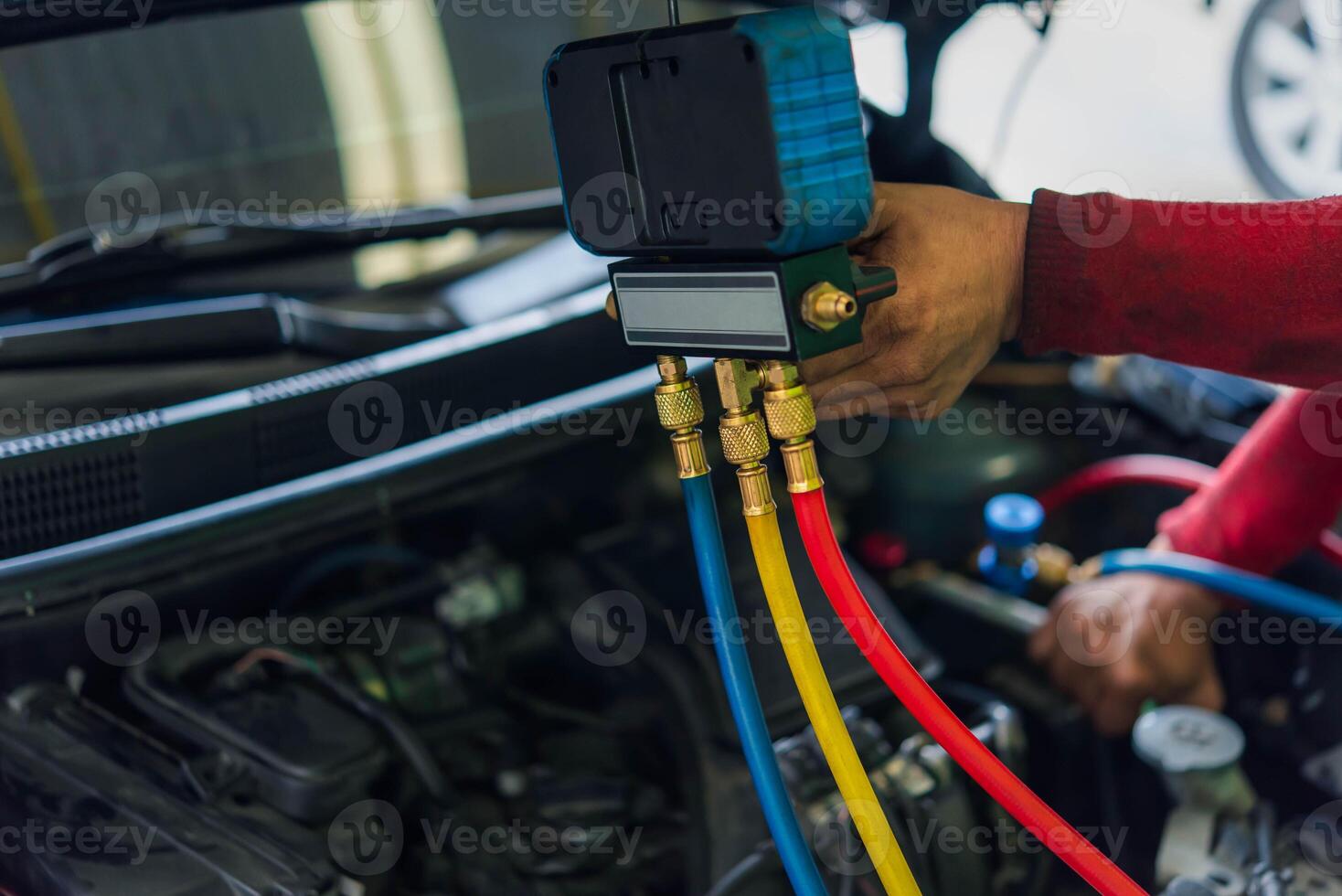 A man is holding a hose and using a tool to check the engine photo