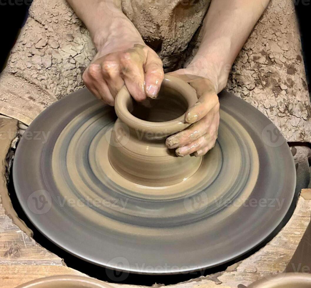 Hobbies and creativity. Closeup of clay product being made on pottery wheel. Hands of young craftsman forming clay pot on pottery wheel. photo