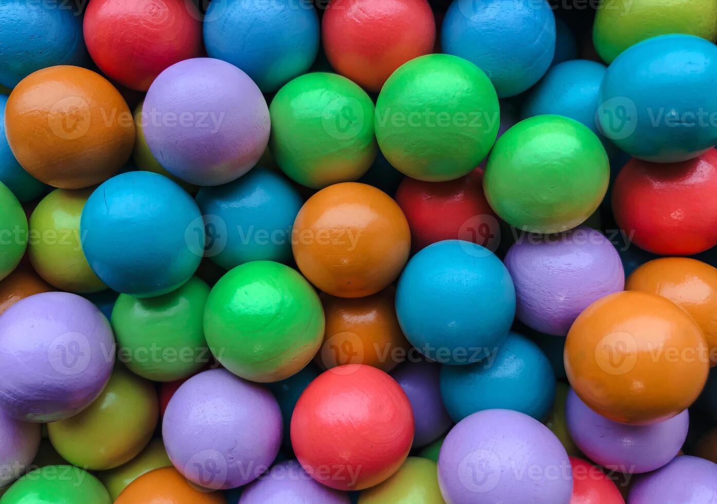 A vibrant and colorful overhead shot of numerous wooden or painted balls, tightly packed together, creating a lively full-frame texture. photo