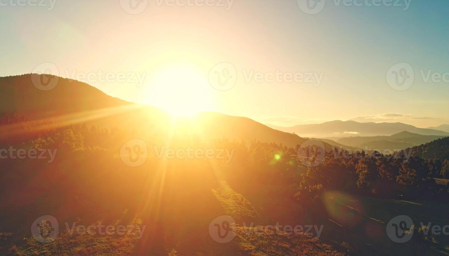 Brilliant Golden Sunrise Erupting Over a Serene, Forested Mountain Range photo