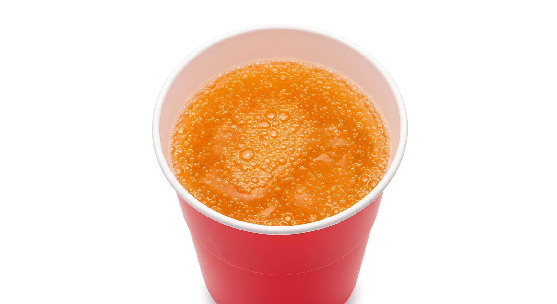 A cup of orange juice sitting on top of a white surface photo
