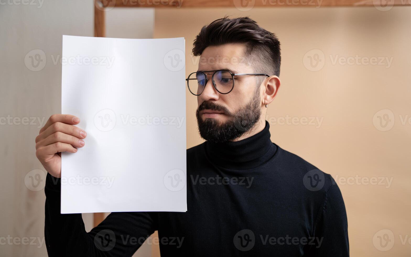 A man with glasses holding up a blank sheet of paper photo