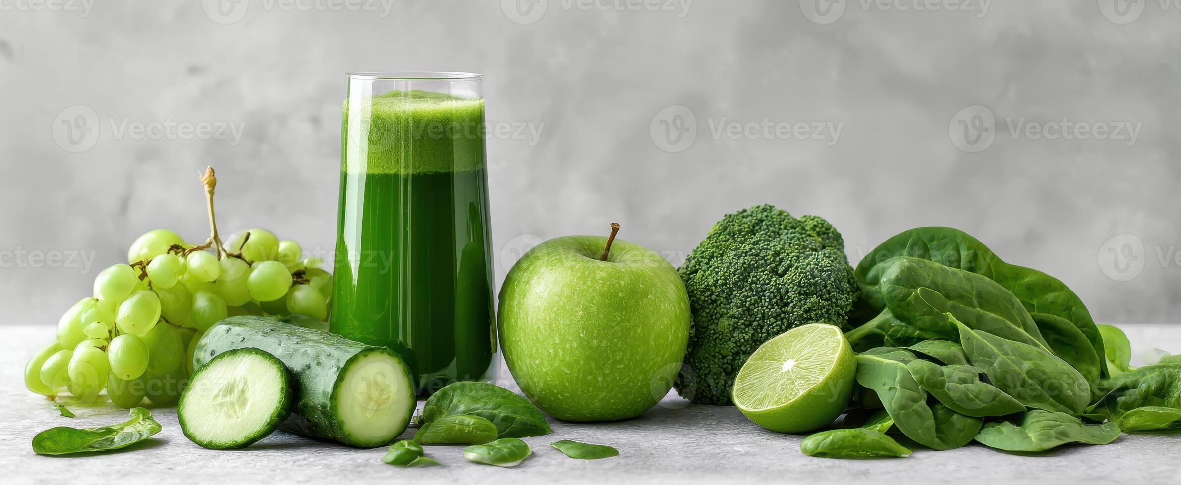 The vibrant green juice surrounded by fresh fruits and vegetables on a table. photo