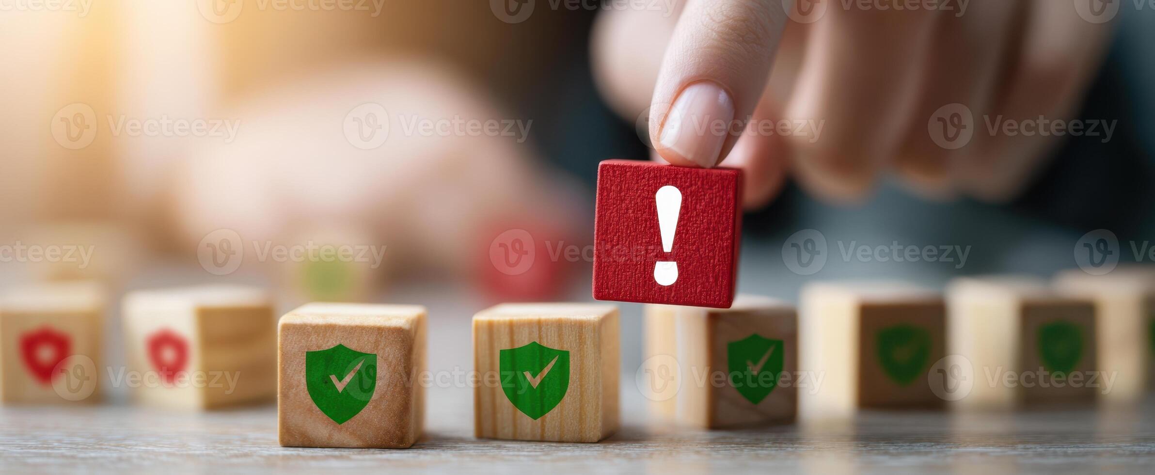 The hand selecting a warning block among green shield icons on a table. photo