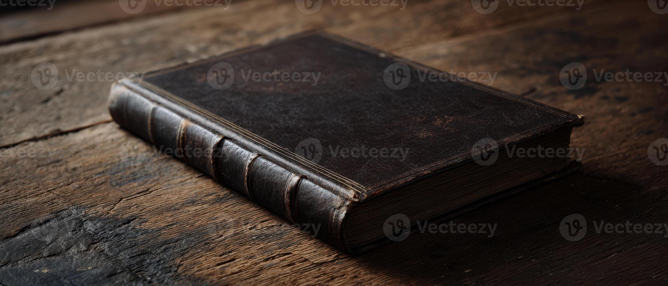 The antique leather-bound book resting on a rustic wooden table. photo