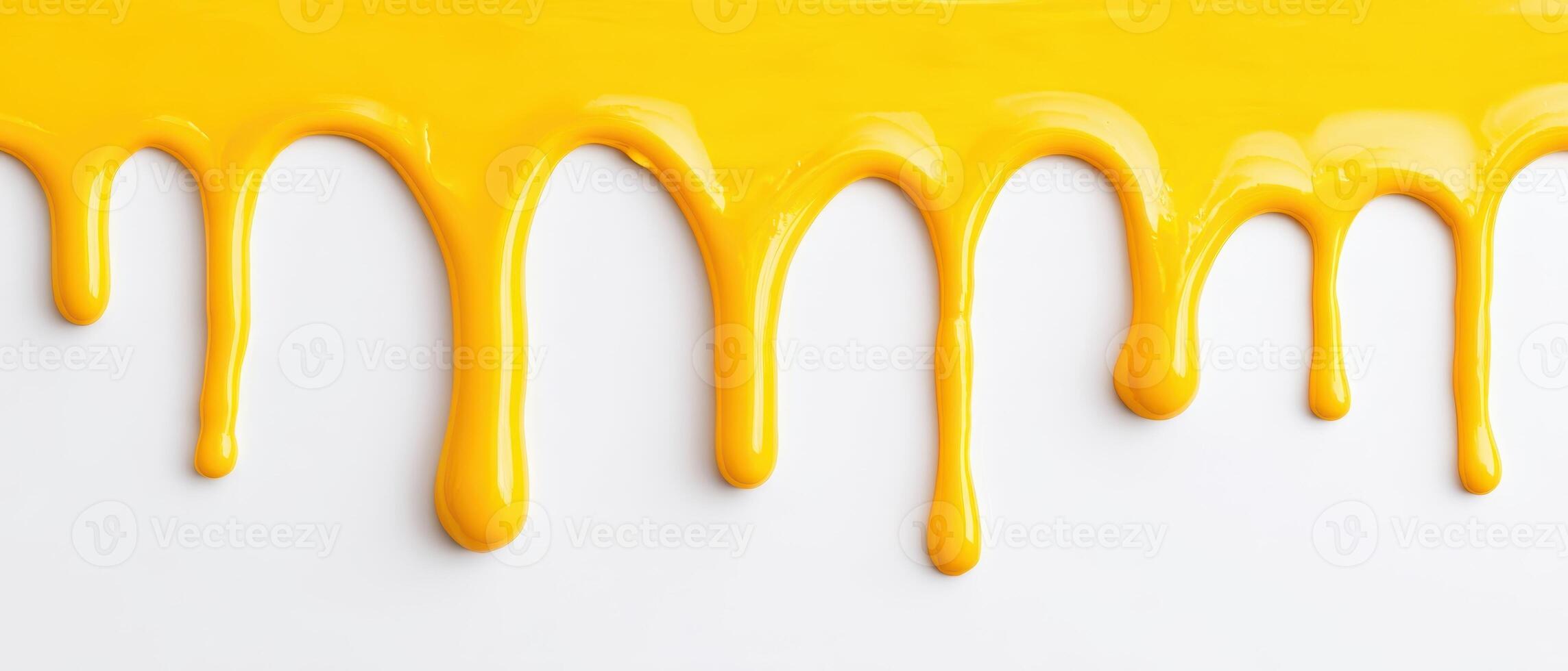 The vibrant yellow paint dripping smoothly across a white background photo
