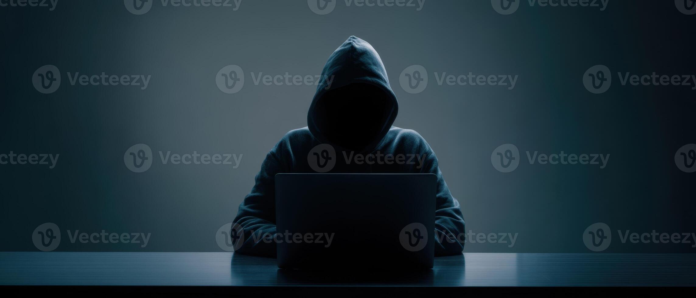 The mysterious hacker working on a laptop in a dark environment. photo