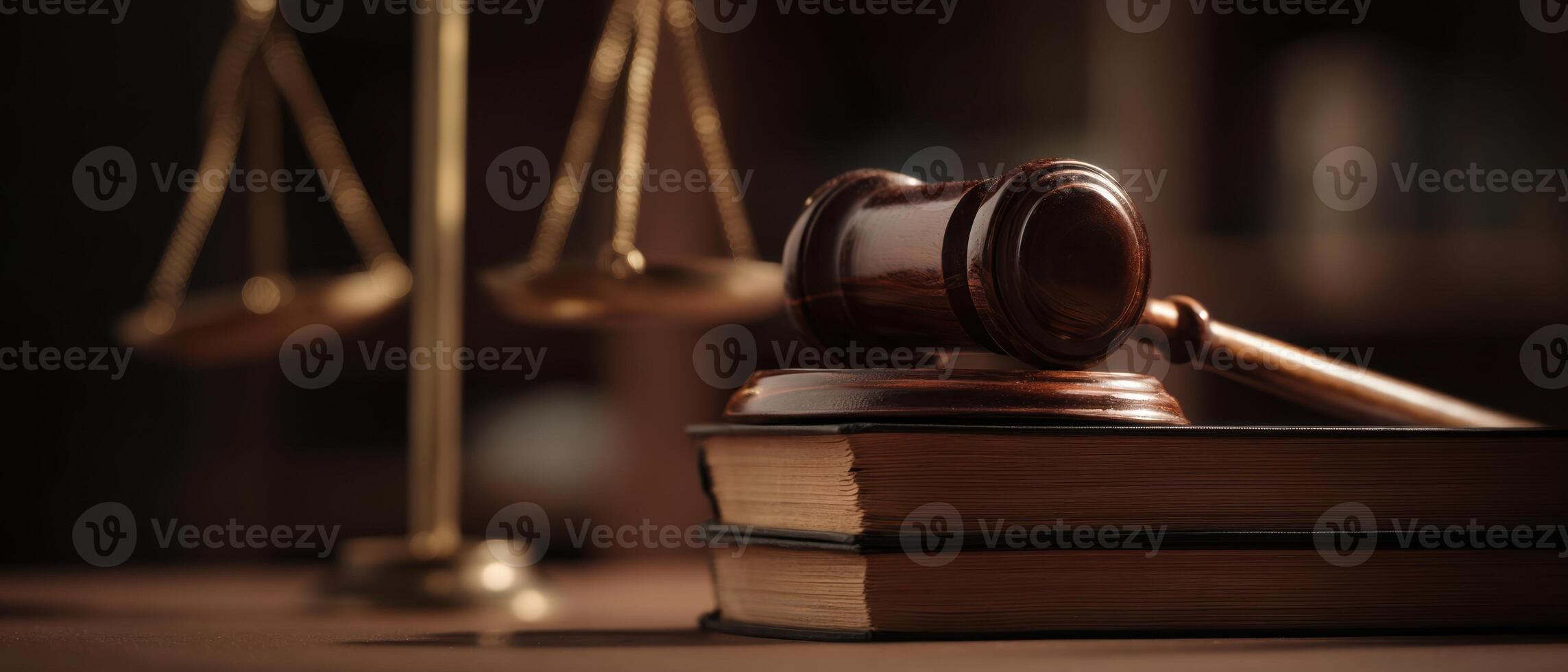 The gavel resting on law books beside scales of justice in a courtroom setting. photo