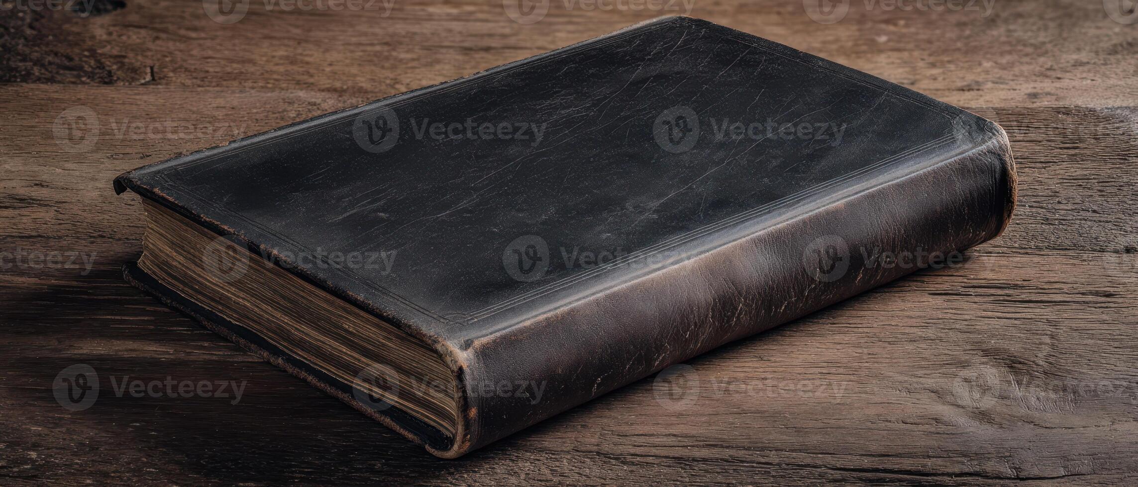 The rustic leather-bound book resting on a wooden table. photo
