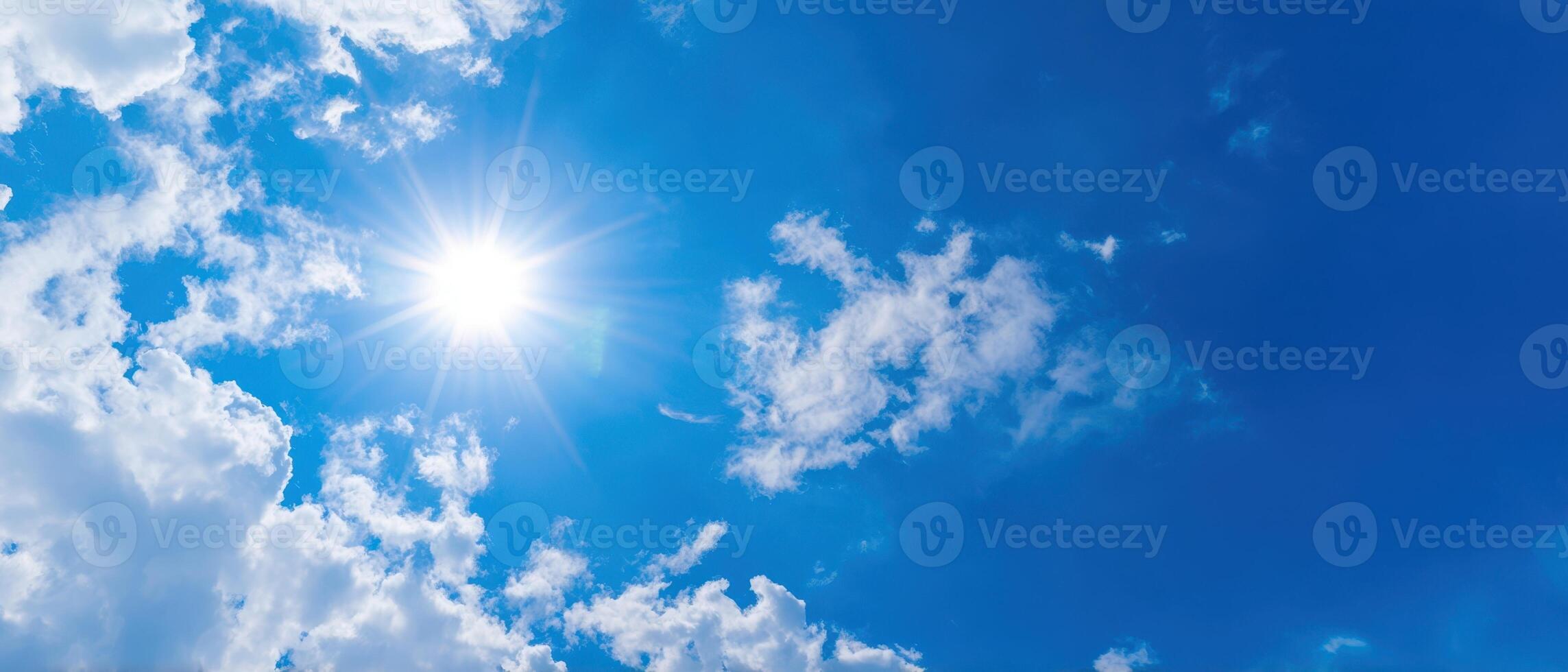 The beautiful sun shining through fluffy clouds in a vibrant blue sky. photo