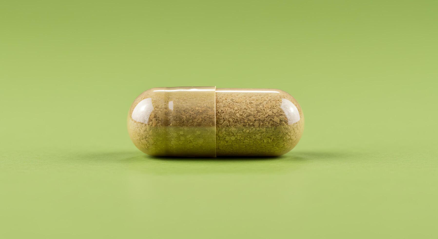 A pill on a green surface with a close up of the pill photo