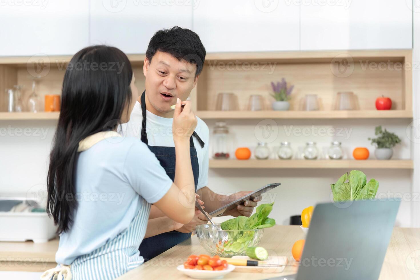 Healthy Cooking. Woman Tasting Fresh Ingredients with Friend in Kitchen photo