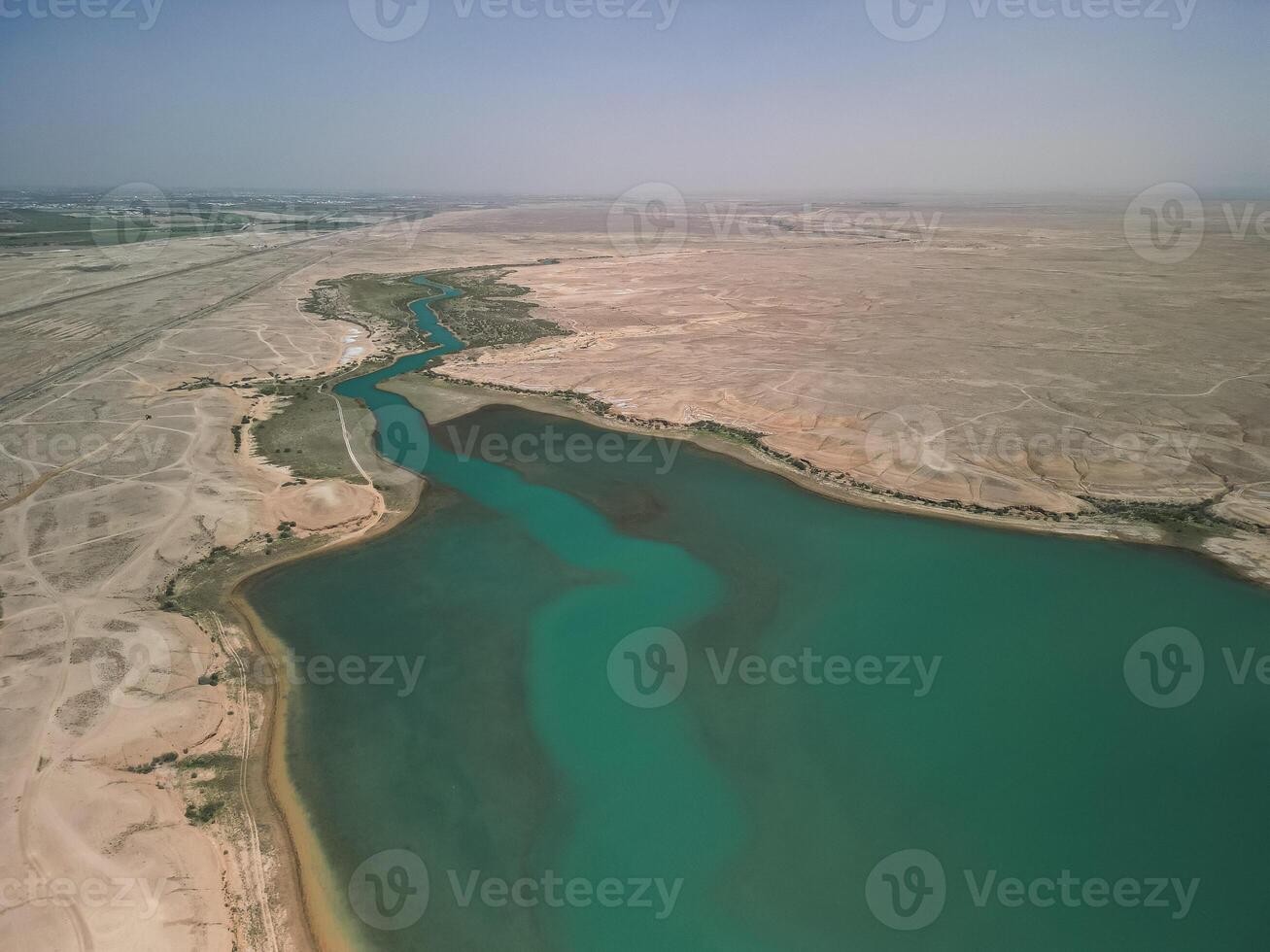 River delta, turquoise reservoir merging with dry steppe in central Uzbekistan photo