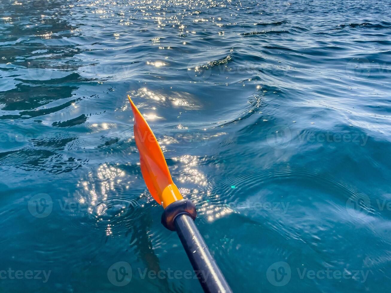 Paddle Water Kayaking - Close-up of a red and black paddle moving through turquoise water on a sunny day. photo