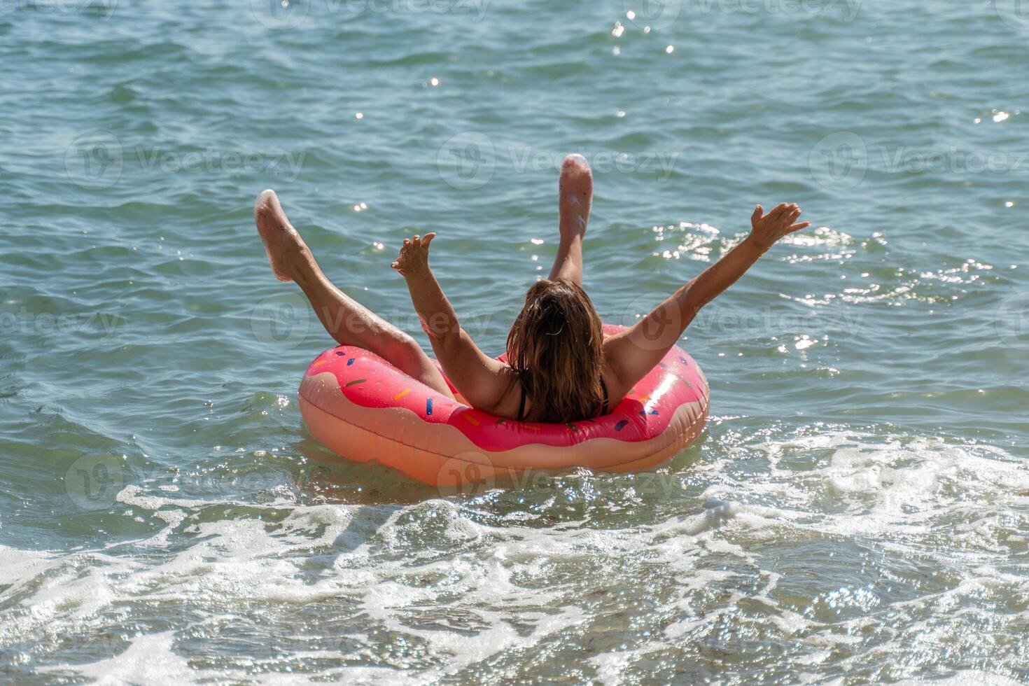 Woman, Inflatable Ring, Sea - Happy woman enjoying a sunny day floating in a ring in the sea. photo