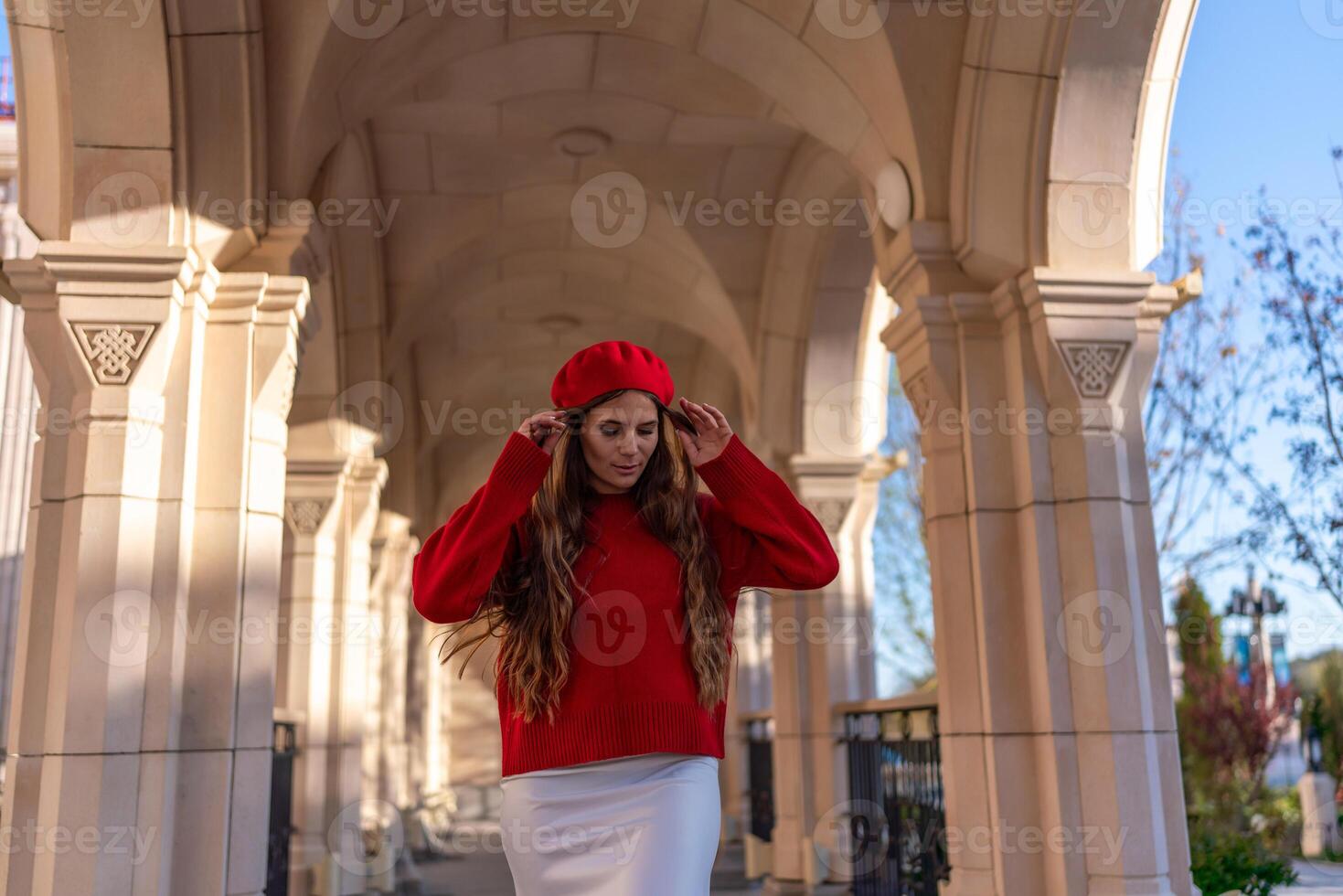 Beret Fashion Woman. Woman adjusts beret under arched walkway, sunny day for photoshoot or style shoot. photo