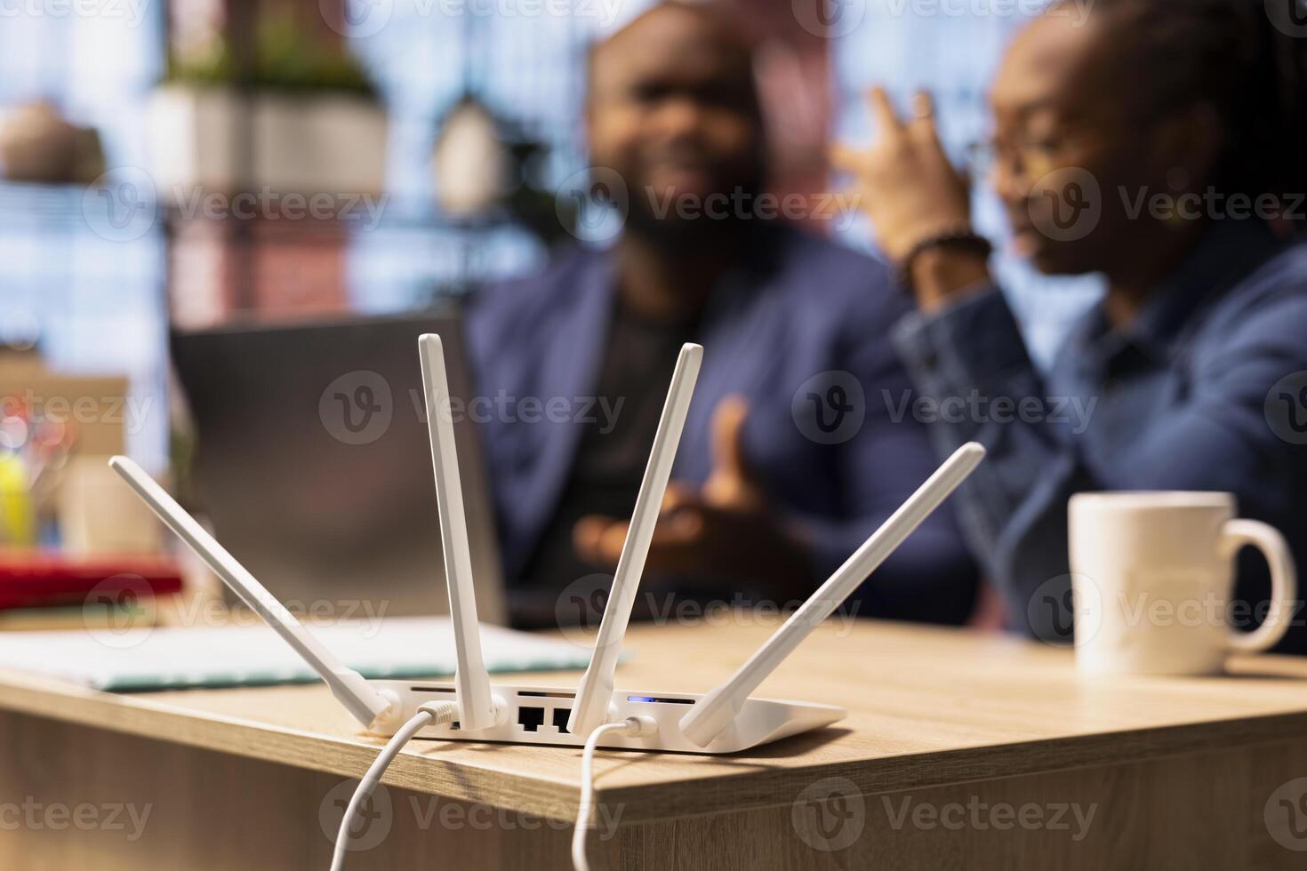Frustrated African American woman tries to reset the Wi Fi modem while her partner checks laptop settings, troubleshooting network errors affecting their online work and browsing experience. photo