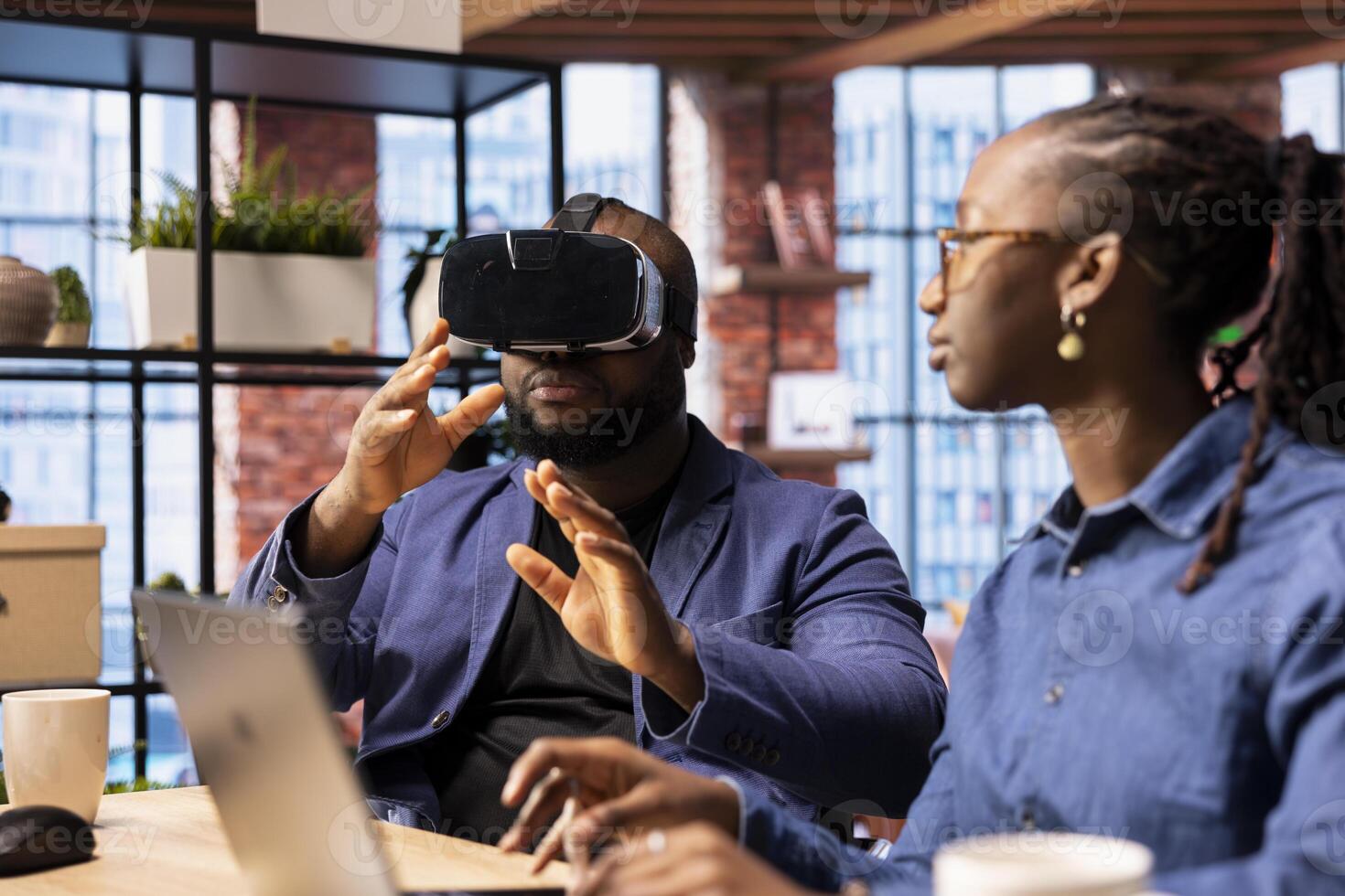 Black people integrates VR and AI into their daily routine where the man engages in immersive 3D experience. Young focused woman managing the animation within the metaverse on laptop. photo