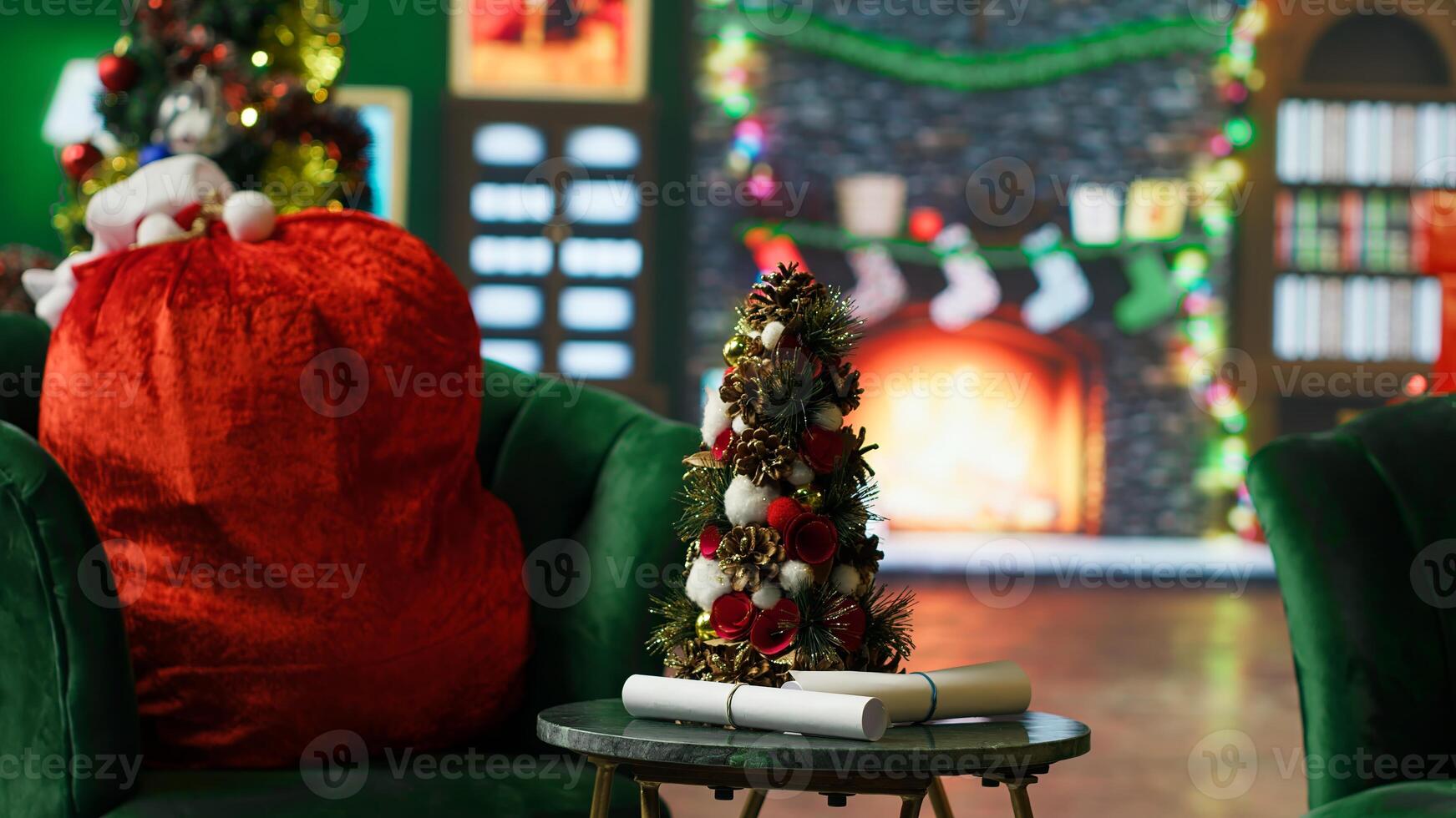Fire burning in empty room fireplace decorated with Christmas tree, lights and other ornaments during winter holiday season. Christmas stockings and paintings above fireside in Santa Claus workshop photo