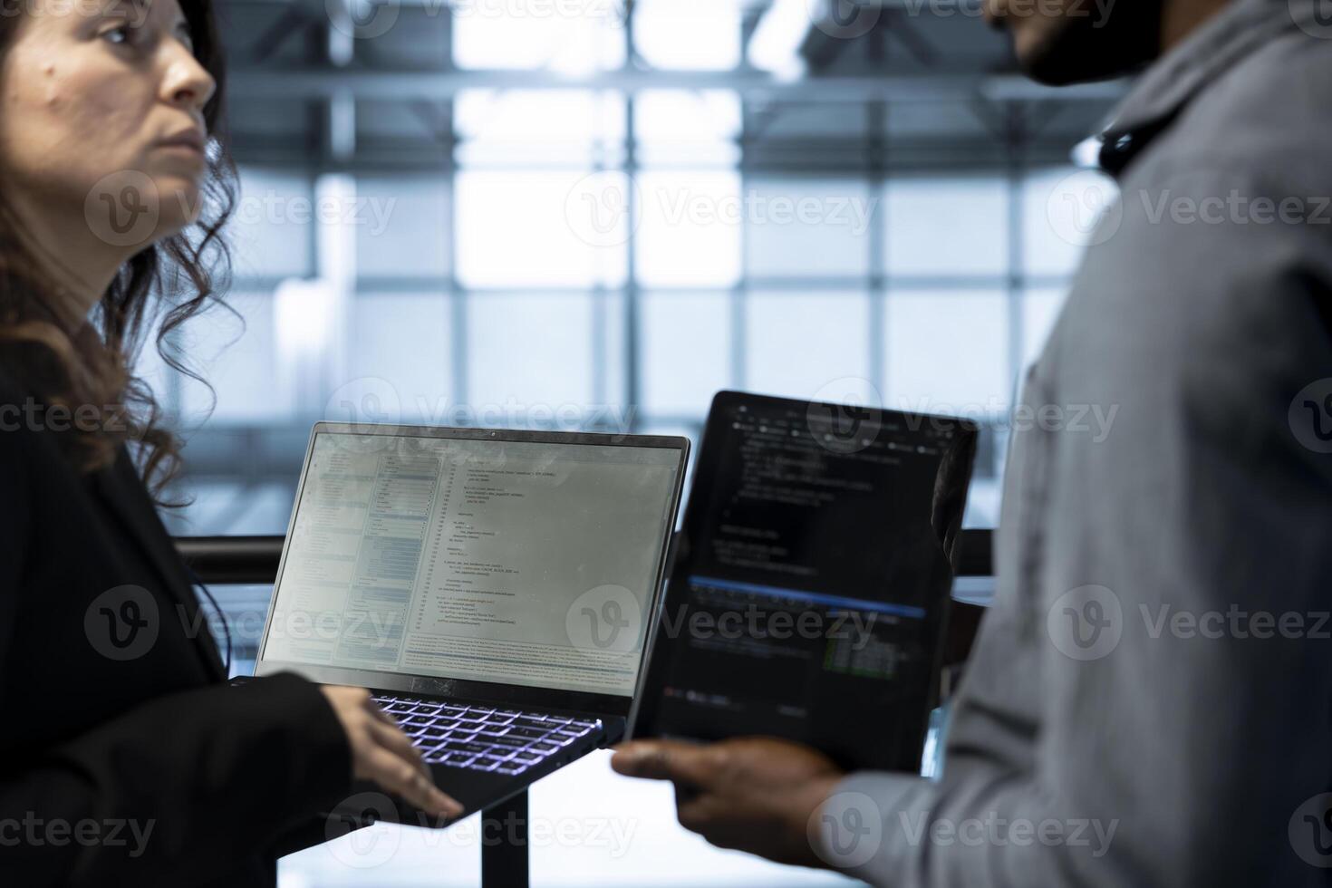 Programmers in data center using devices, executing security patches, verifying firewall configurations, performing vulnerability scans, tracking suspicious activity, ensuring data protection photo