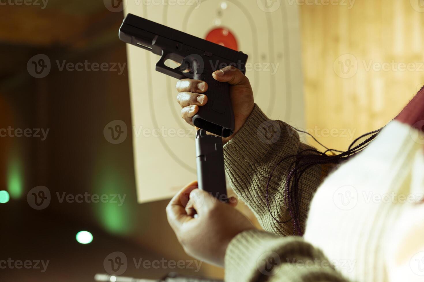 Close up of person reloading magazine into pistol during firearm practice session at indoor shooting range, learning safety practices. Shooting range client loading gun, doing self defense preparation photo