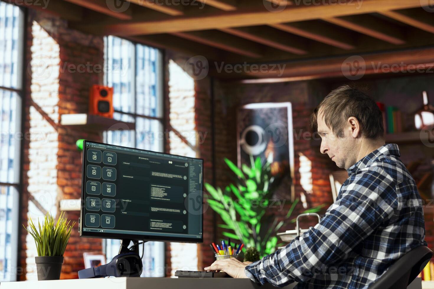 Man seated at desk speaking with AI LLM chatbot software in modern home office. Person communicating with large language model program on computer in bright apartment room photo